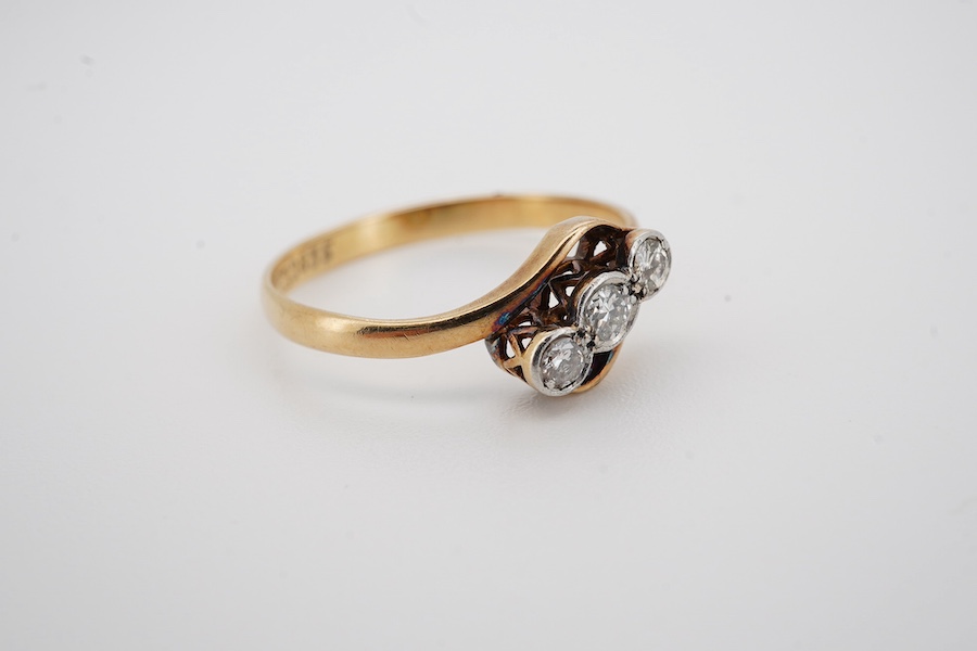 An 18ct, plat. and three stone diamond set crossover ring, size P, gross weight 2.1 grams. Condition - fair